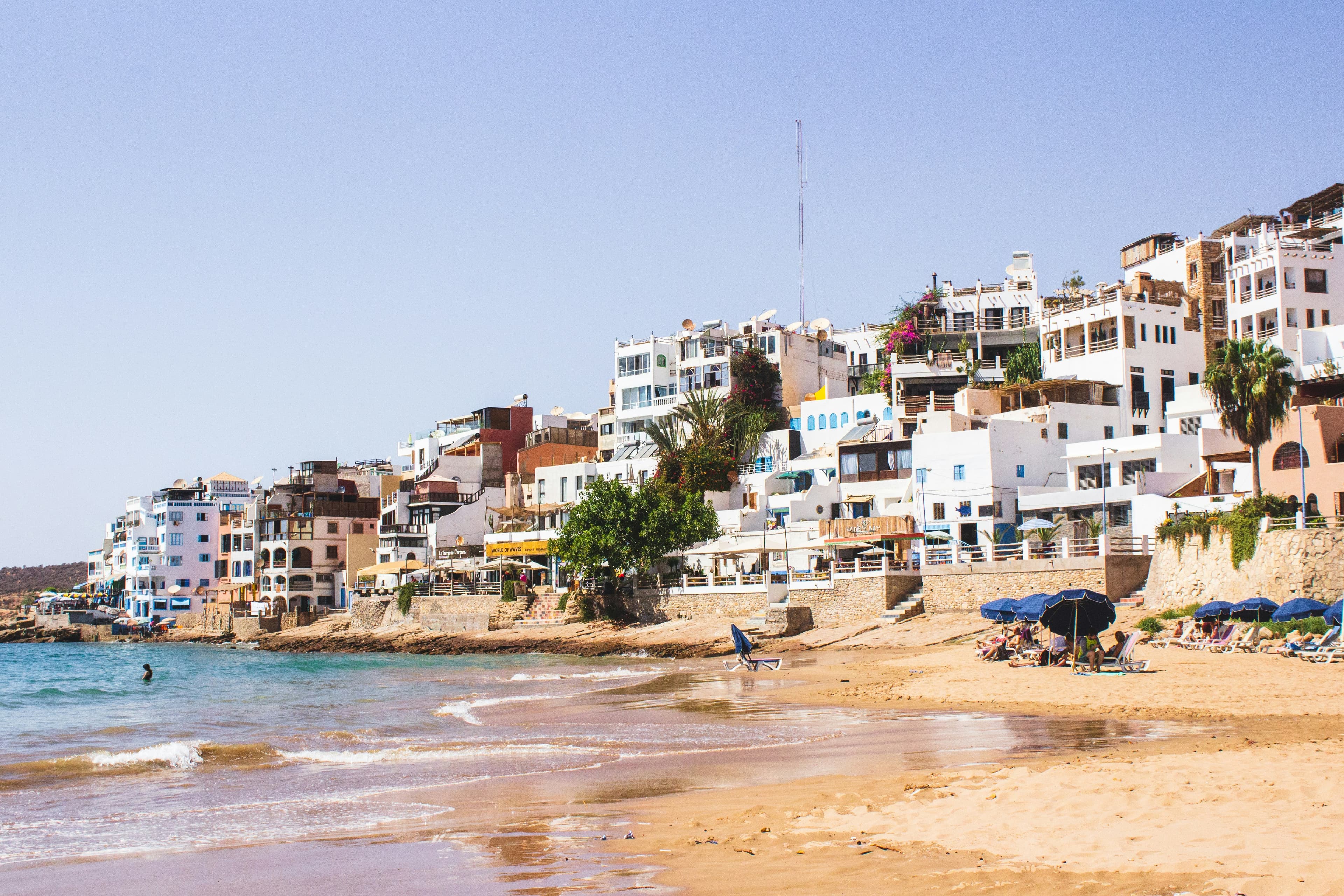 Le village de Taghazout près d'Agadir, maisons blanches au-dessus de la plage, parasols et baigneurs