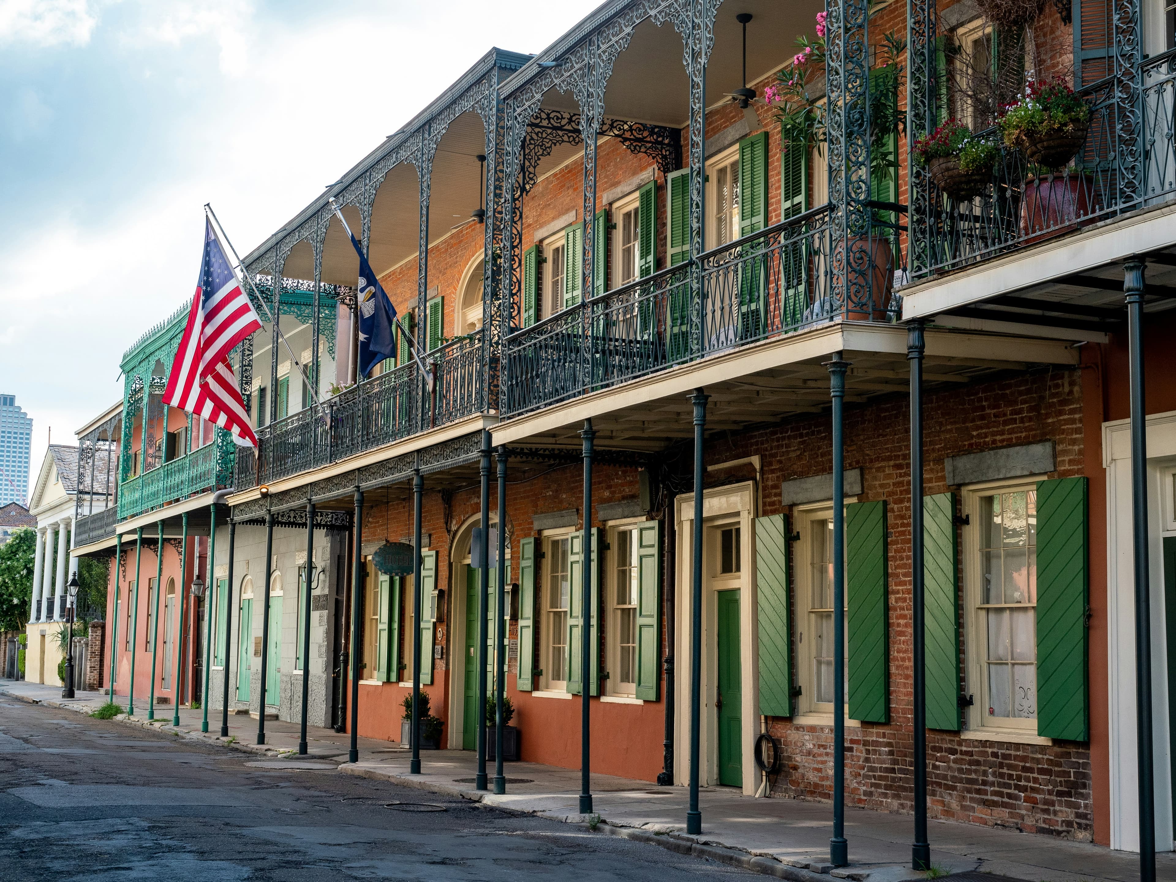 French Quarter street with iron balconies, green shutters and an American flag