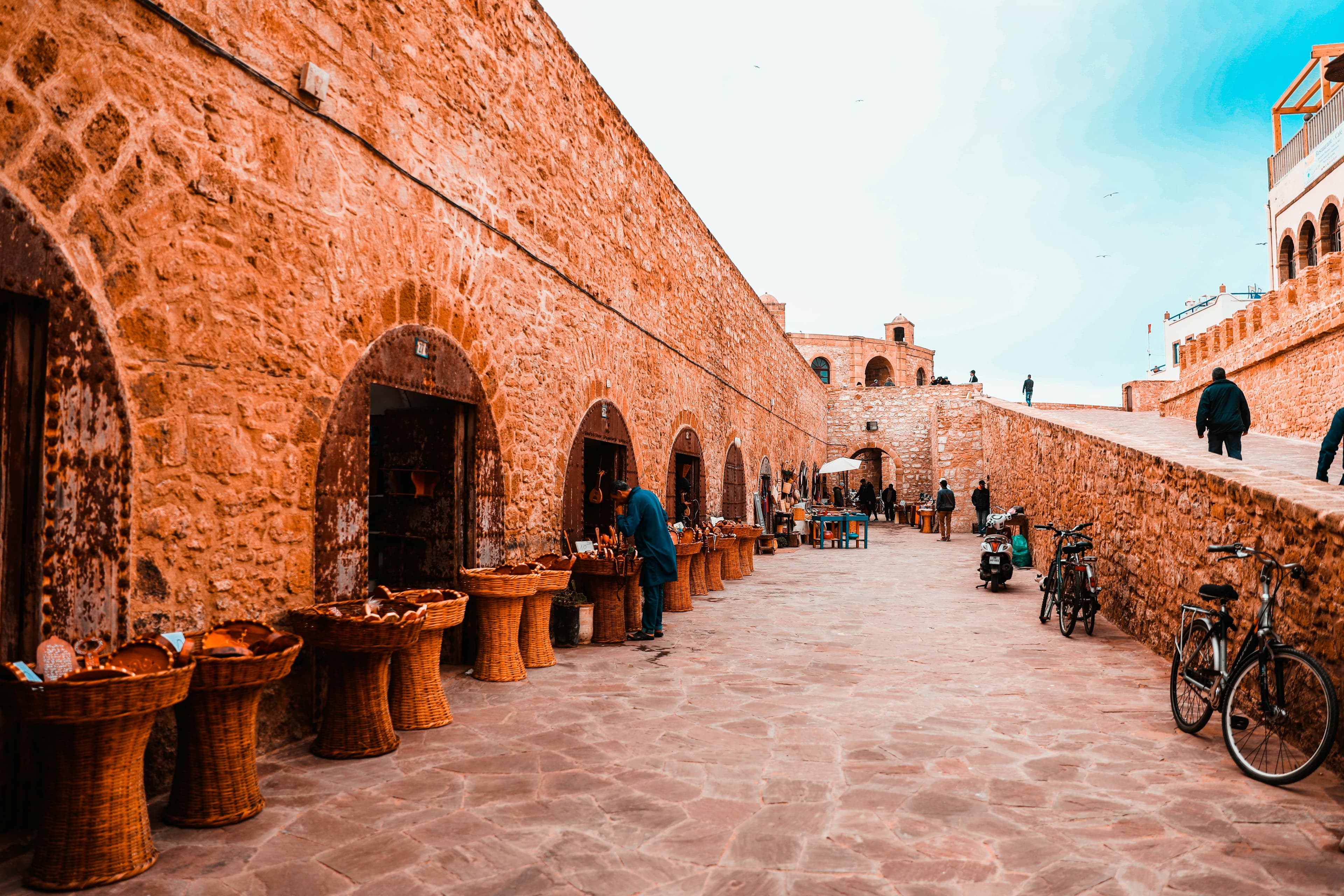 Des passants sur les remparts de brique d'Essaouira, au-dessus du port