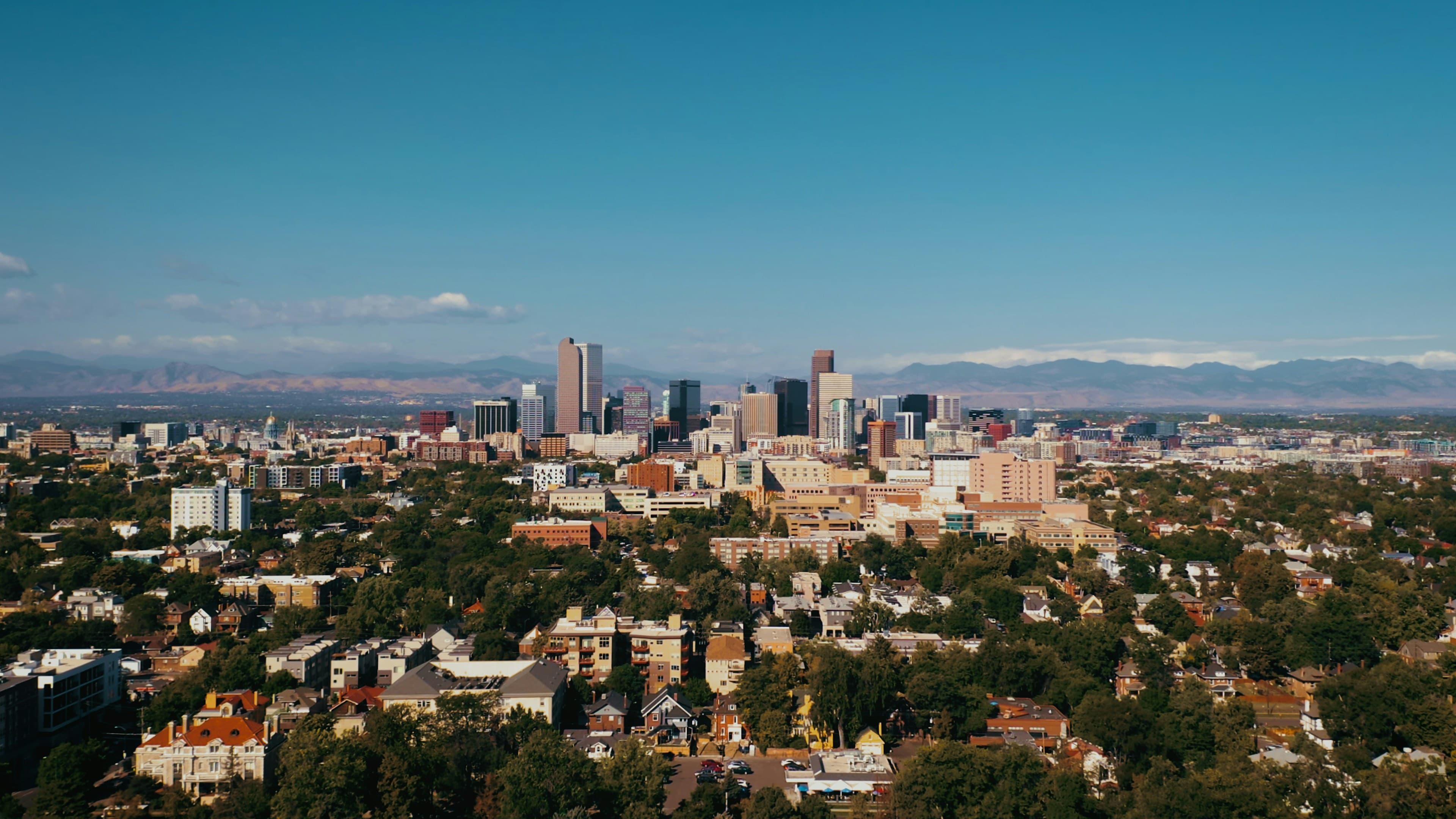 Downtown Denver skyline with the Rocky Mountains on the horizon under a clear sky