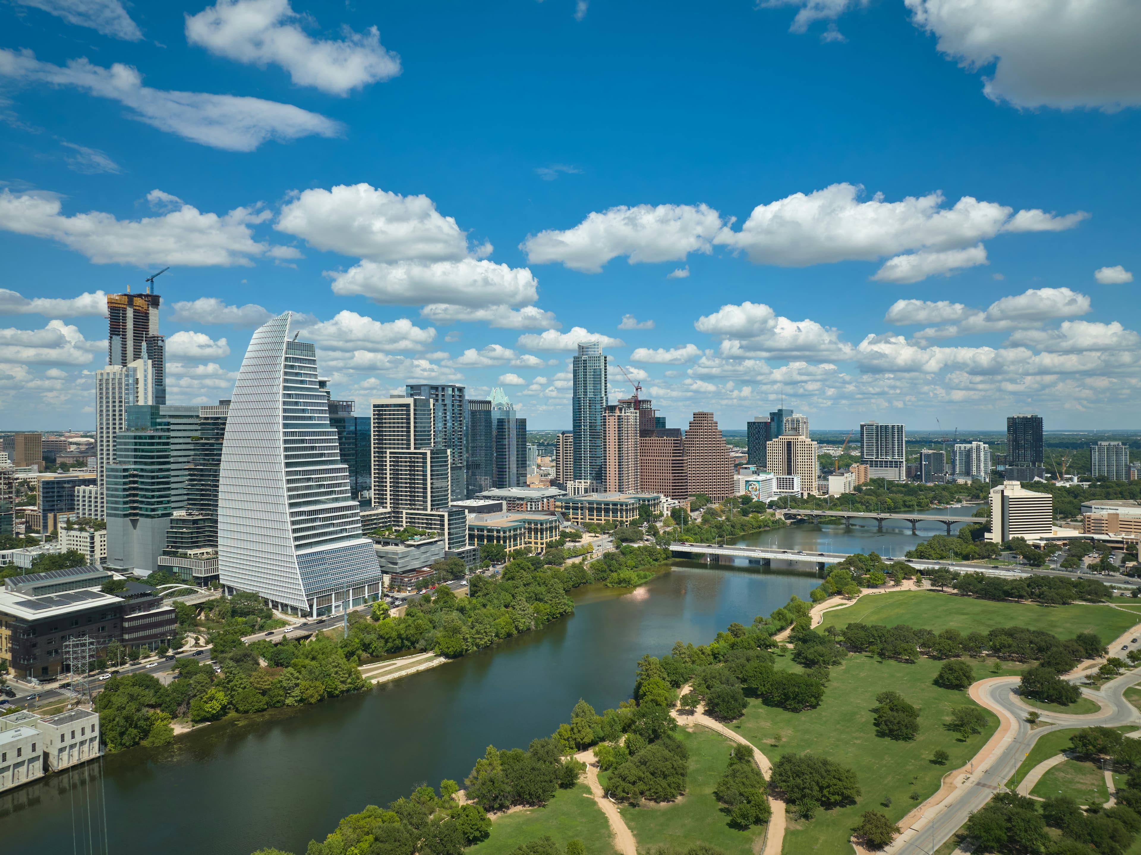 Downtown Austin skyline above Lady Bird Lake and green parkland under a blue sky
