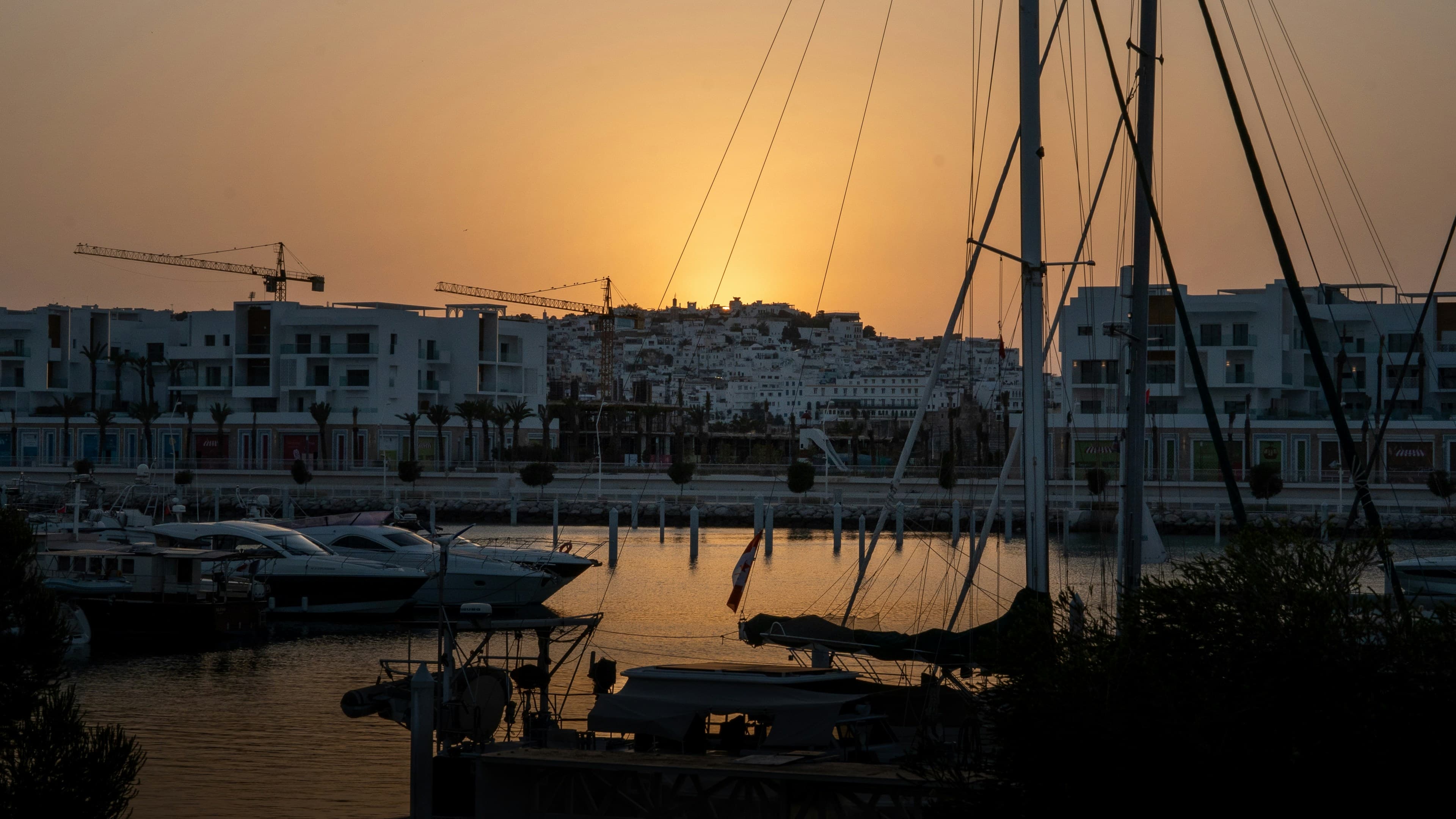 La marina de Tanger au coucher du soleil, voiliers amarrés et médina blanche sur la colline