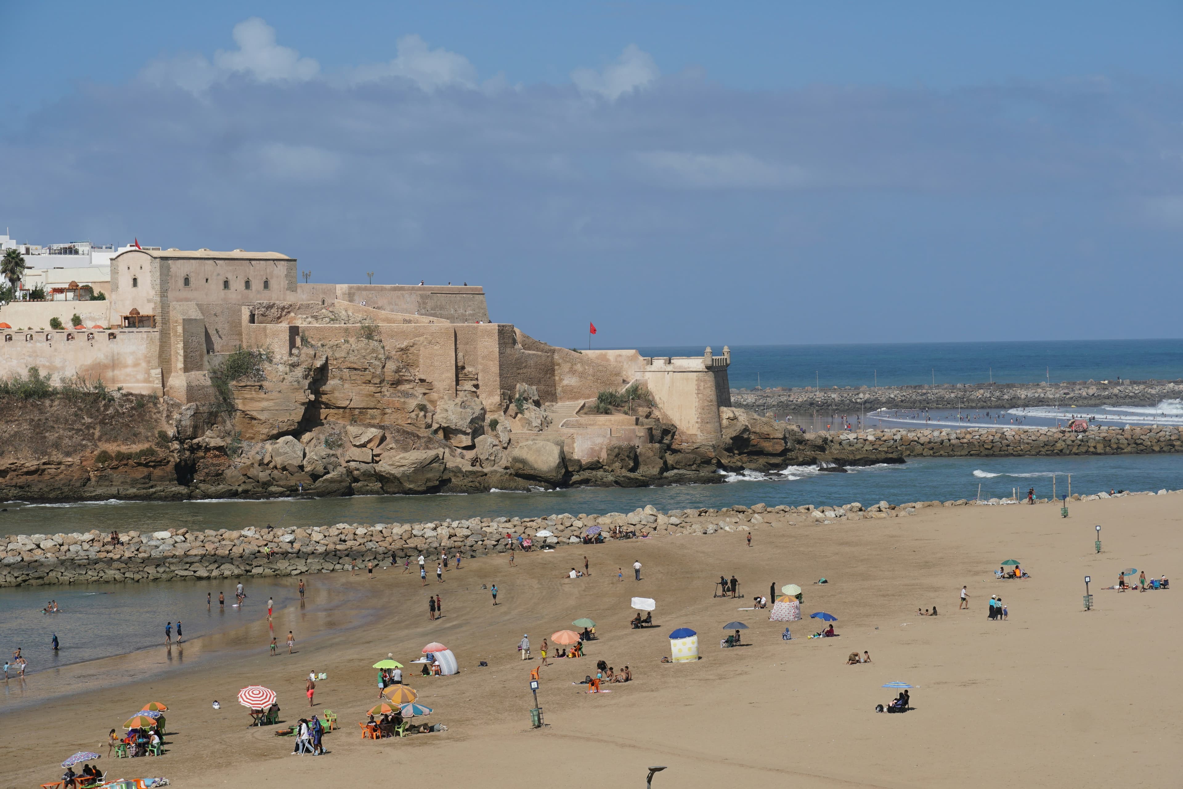 La kasbah des Oudayas à Rabat vue de la plage, baigneurs et parasols à l'embouchure du Bouregreg