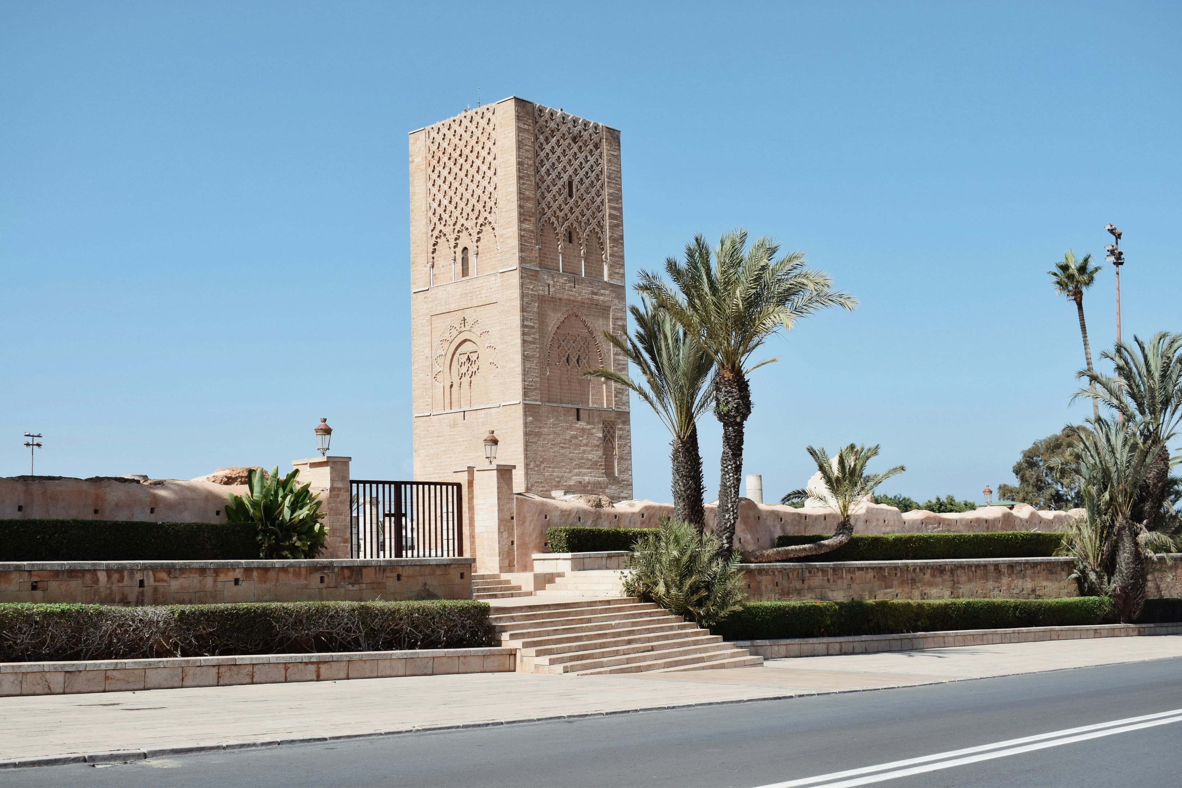 La tour Hassan à Rabat, minaret de pierre ocre entouré de palmiers sous un ciel bleu
